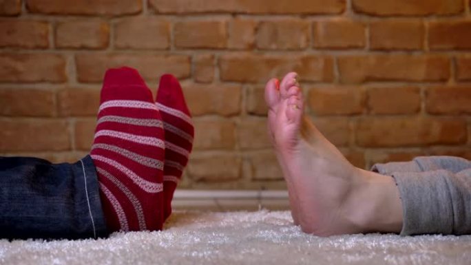 女性和男性的双腿相对躺着，在毛茸茸的地毯上快乐地移动。