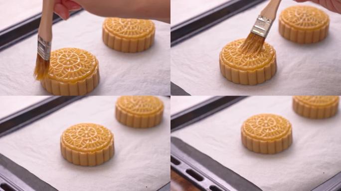中秋节月饼的制作过程-女士烘烤前在糕点表面刷蛋液。节日自制概念。