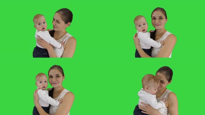 母亲抱着孩子，看着相机在绿色屏幕上微笑，色度键