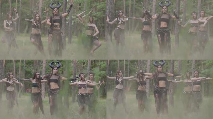 一群化妆的女舞者，穿着神秘的神话般的服装，在彩烟中跳舞。