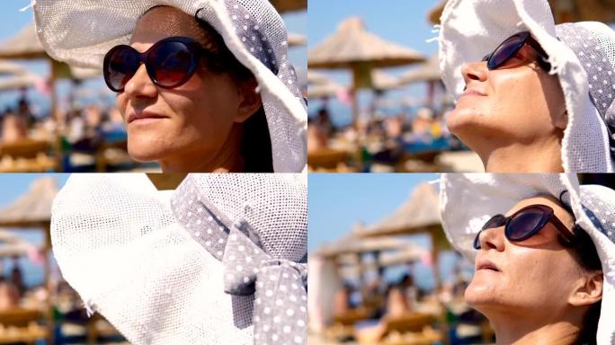 美丽的年轻女子戴着沙滩帽和太阳镜在热带度假胜地微笑