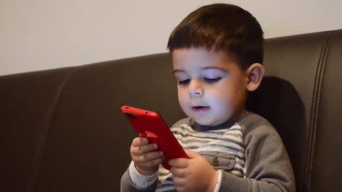 可爱的两岁男孩在智能手机上与某人交谈。