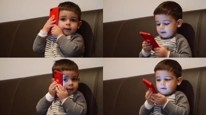 可爱的两岁男孩在智能手机上与某人交谈。