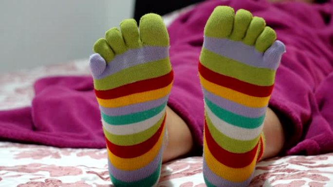 穿着袜子的女性腿，脚趾在床上放松