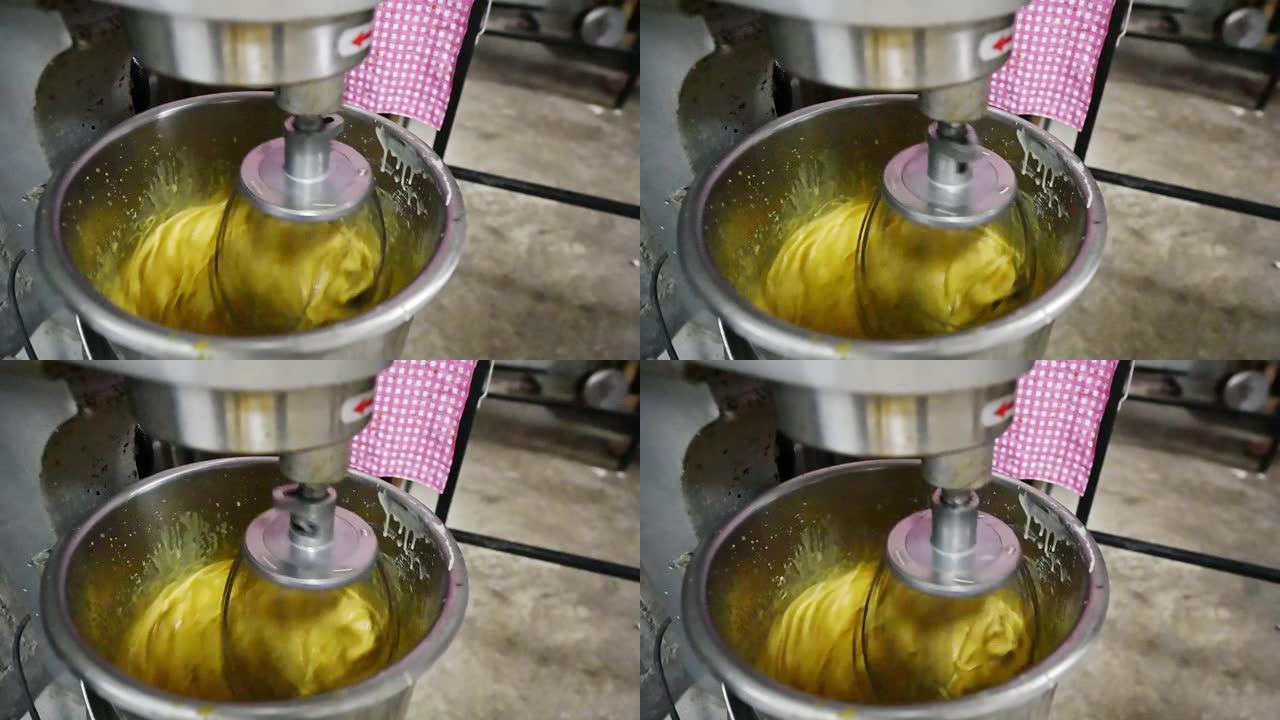 碗中混合蛋黄和配料的电动不锈钢手动搅拌器的慢动作