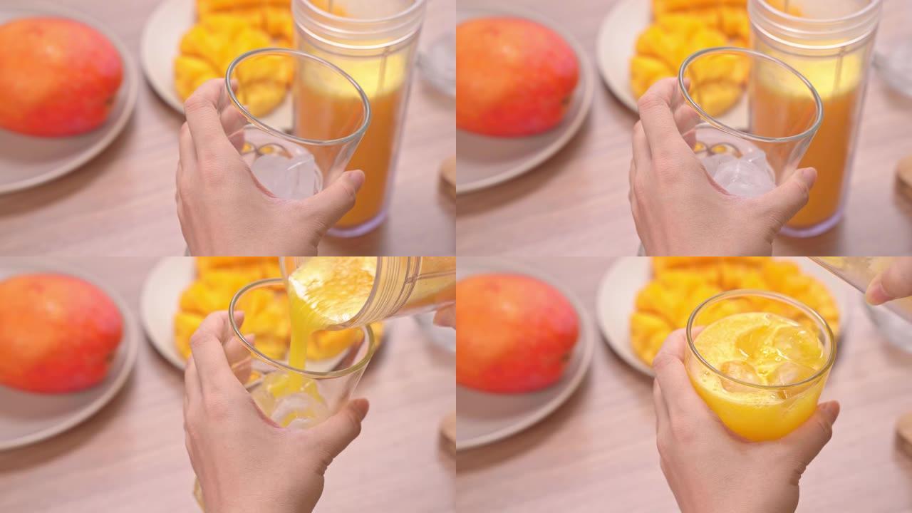 女人在明亮的木桌背景下在夏季厨房制作新鲜芒果汁。健康的自制概念。