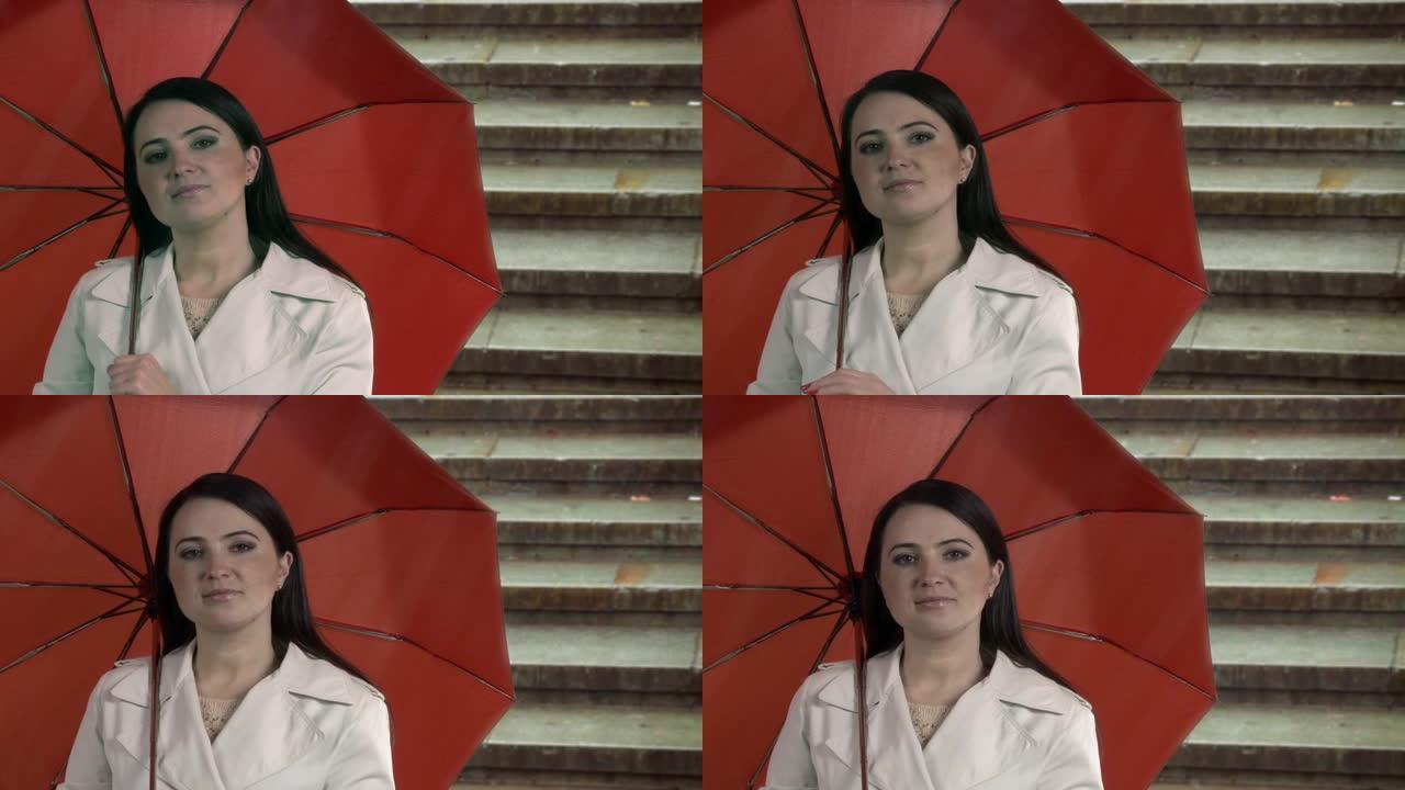 在城市街道的雨中拿着红色雨伞的女人。