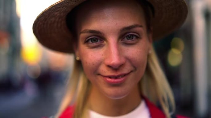白人年轻女子的特写肖像，自然妆容站在街上，慢动作对着镜头微笑