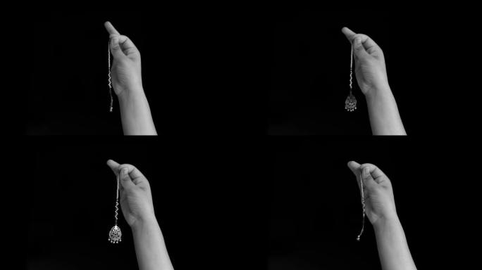 一只女性的手举起，在黑色背景上孤立地展示了maang tikka (女士在发际线上佩戴的印度珠宝)。