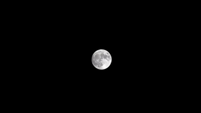 满月在夜空中移动，没有云。4k镜头，时间流逝。神秘的月亮从下到上移动。月光照在黑色的夜空中。