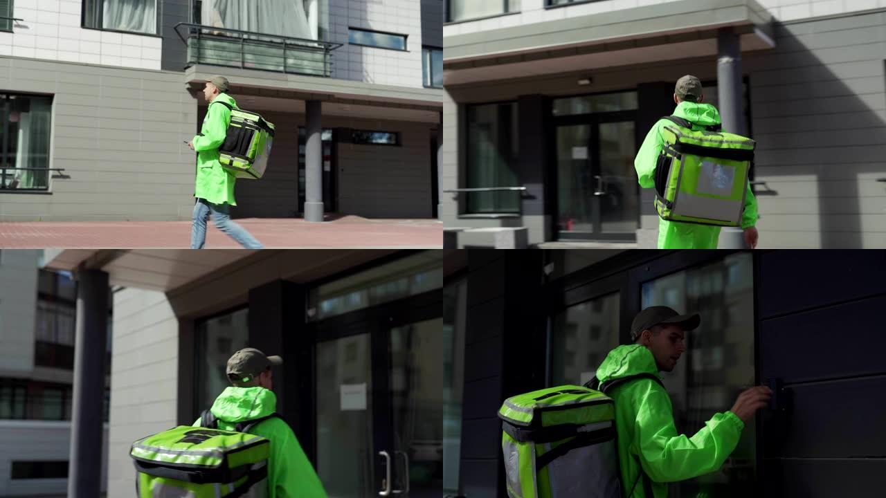 用手机导航的年轻男性食品快递员带着隔热背包走在街上的追踪照片。送餐员来到家门口，打门铃并与客户交谈