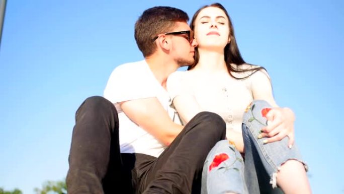 浪漫幸福的夫妻坐在绿草地上，靠着天空。夫妻信任、爱和幸福的概念。完整镜头。