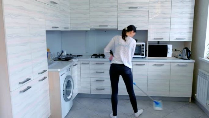疲惫的女人用拖把洗厨房地板。