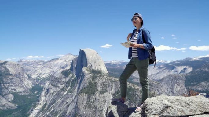 徒步旅行者站在山顶上，带着地图