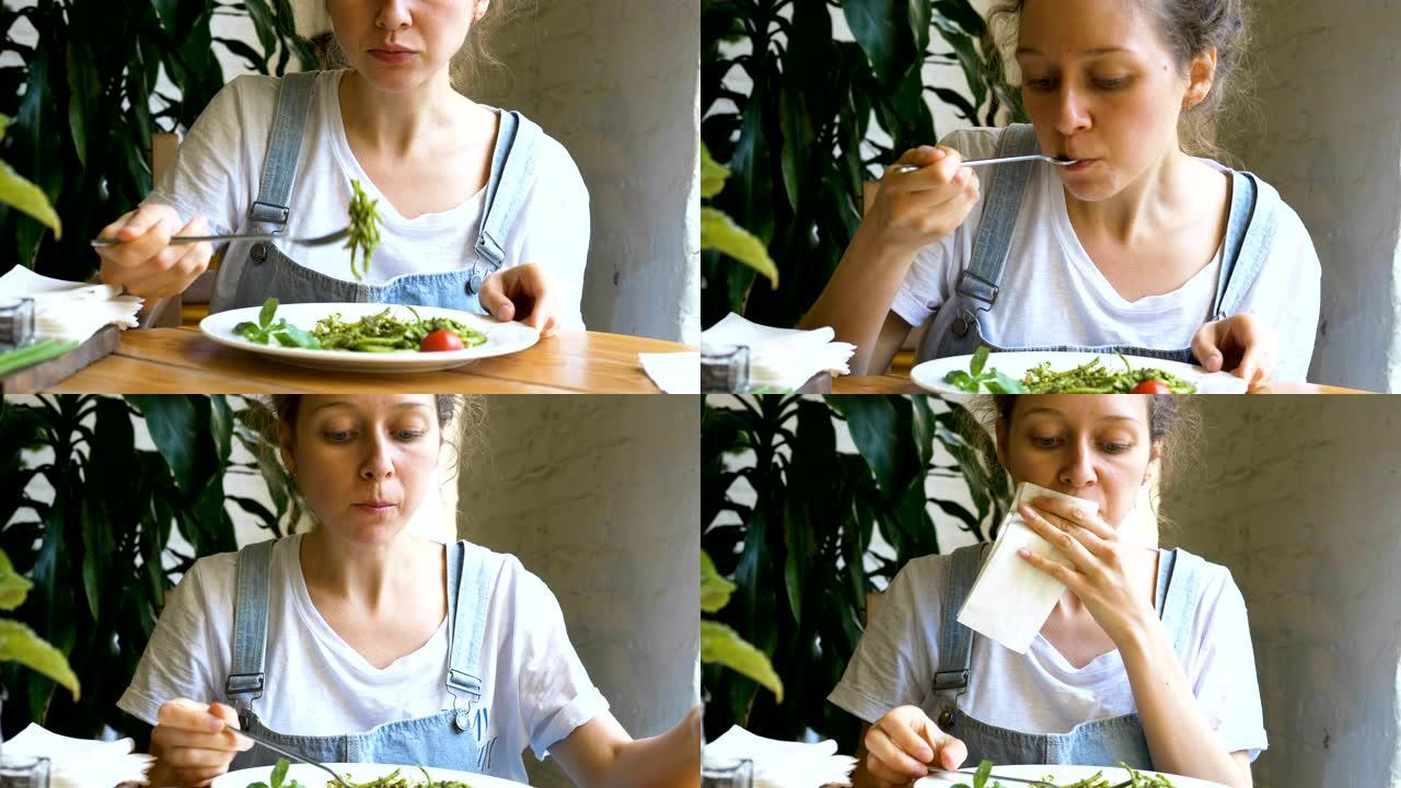 美丽的黑发女人吃绿色新鲜沙拉和擦嘴