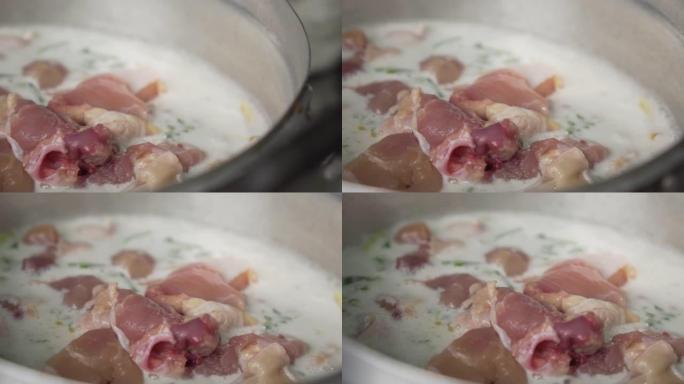 泰国高良姜鸡汤放在沸腾的锅里。从生鸡肉开始。慢动作