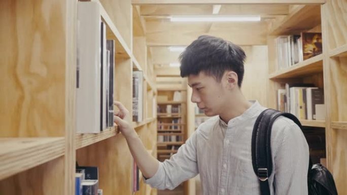年轻的亚洲男大学生在图书馆寻找书籍 (慢动作)