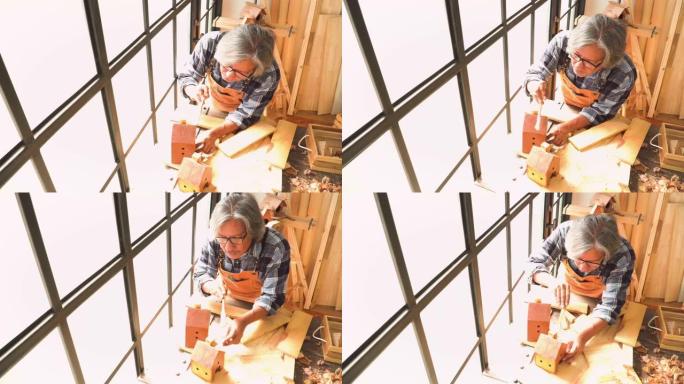 高角度视图: 高级木匠用油漆刷清理车间房屋中的木制房屋模型