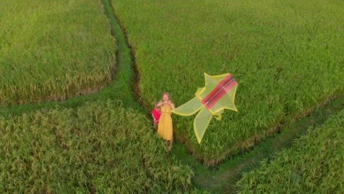 一个年轻女子和她的小儿子在美丽的田野上玩黄色风筝的空中镜头