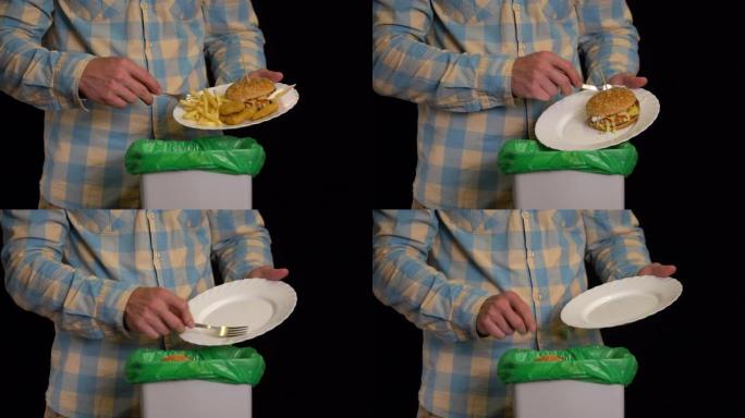男子用盘子将汉堡，炸薯条，金块，奶酪酱刮入垃圾箱。
