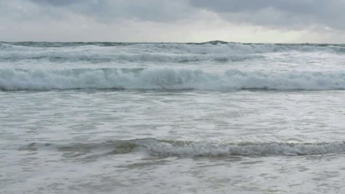 海水的慢动作，大海浪在雨云天空下溅起海滩。