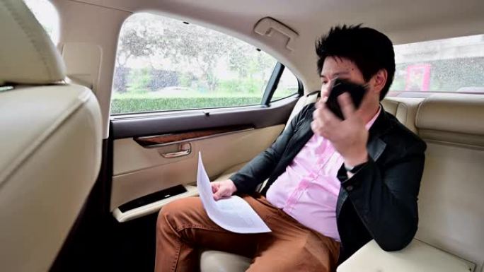 4k亚洲商人坐在车里用手机聊天看文件