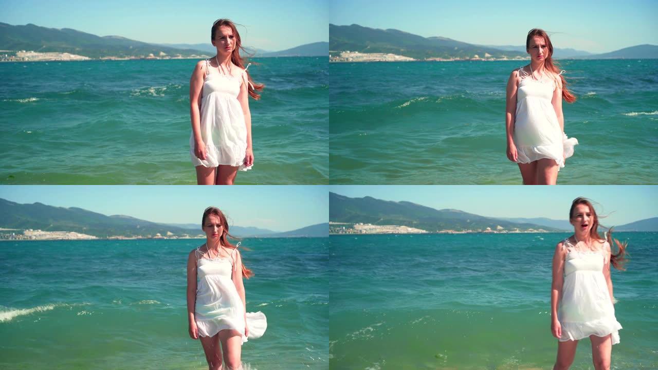 一个穿着白色沙滩装的女孩站在海边。一个光着脚的漂亮女孩站在海边。