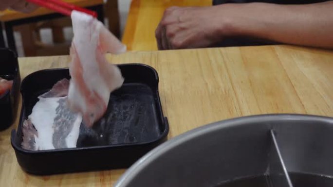 人们喜欢在日本餐厅吃火锅，在热汤中加入猪肉，在火锅中加入美味的猪肉切片。