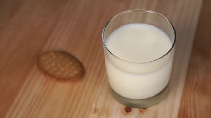 ound燕麦片饼干落在一杯牛奶旁边的木桌上