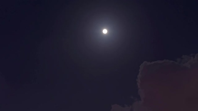 满月在夜空中移动穿过乌云。4k镜头，时间流逝。云层中的神秘月亮从闪耀到完全被乌云覆盖。月光照在黑色的
