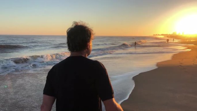 日落时在海滩岸边散步的退休男子