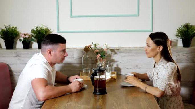 年轻夫妇在咖啡馆的木桌上聊天喝茶
