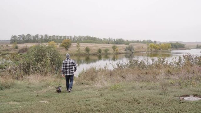 年轻人和可爱的腊肠狗一起去河边，都穿着休闲的背景