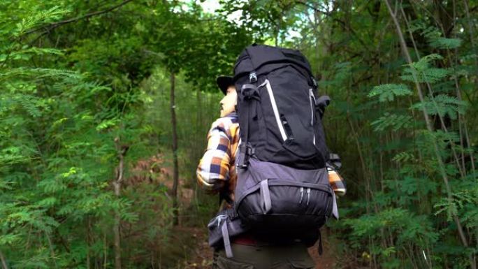 男子旅行者带着背包在自然森林中行走和寻找