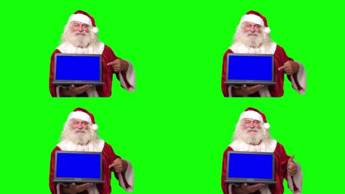 圣诞老人拿着一台笔记本电脑，蓝屏指向它色度键绿色屏幕背景