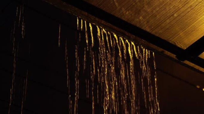晚上屋顶上的雨滴。黄雨特写。
