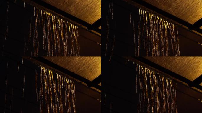晚上屋顶上的雨滴。黄雨特写。