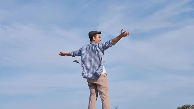 亚洲男子举手蓝天，高山景，生活理念。慢动作。