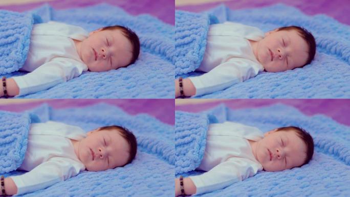 可爱的新生婴儿躺在床上，在被窝下睡得很香。肖像视图。
