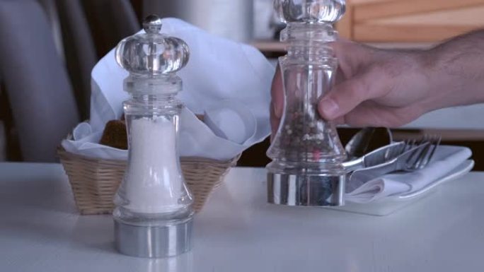男性手在餐厅里的桌子上拿盐和胡椒。在咖啡馆服务。4k
