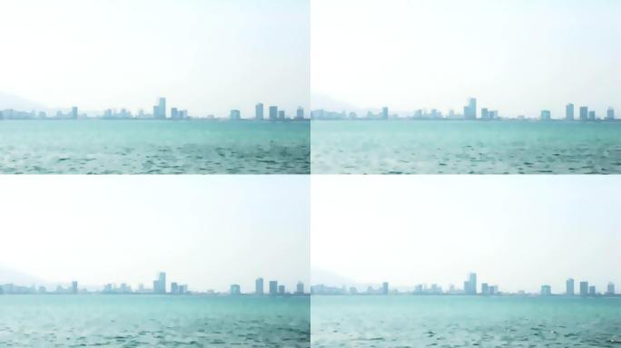 摩天大楼剪影在雾和海模糊的背景视频过渡。阴霾笼罩着地平线上的大海和城市摩天大楼。合成视频素材的背景。