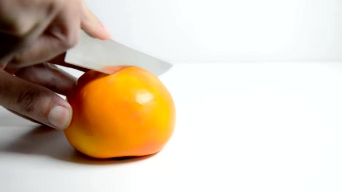 男人的手切成半个新鲜的橙色柿子