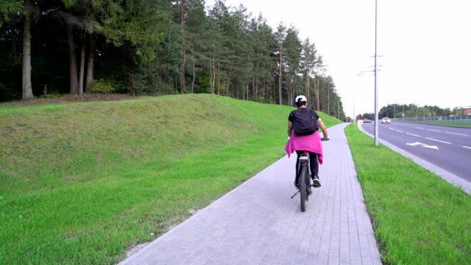 女骑车人，女骑在街上骑自行车，在山上举起，享受体育活动，自行车友好的城市，健康的生活方式