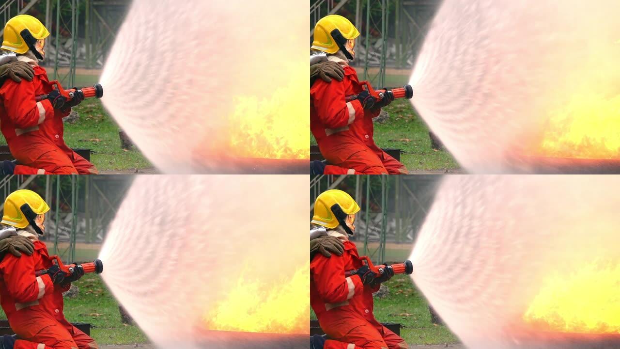 在消防训练班上，穿着消防服的消防员在安全救援任务中使用水管灭火的高清慢动作中等镜头。消防员在燃烧的房