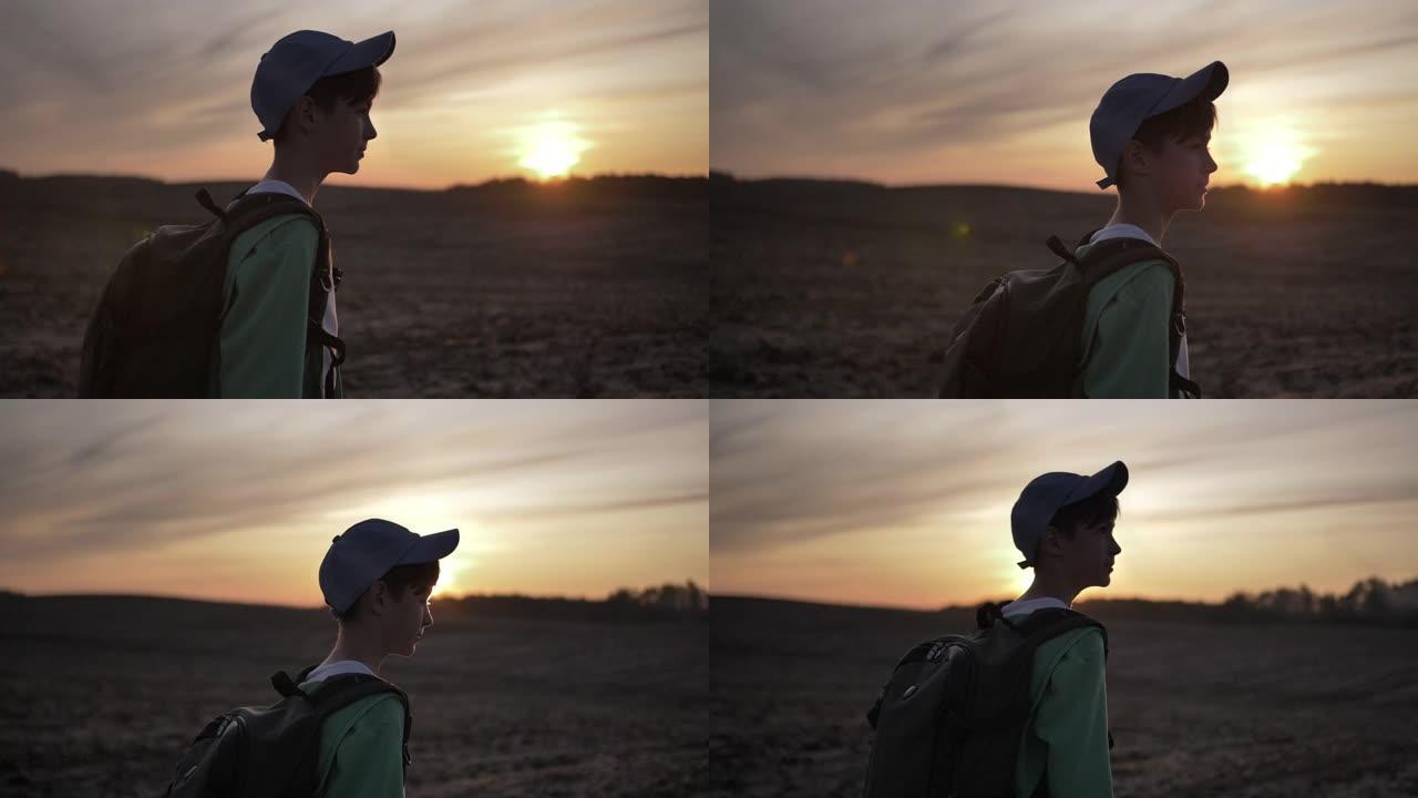 带着背包的旅行男孩在日落时走在户外