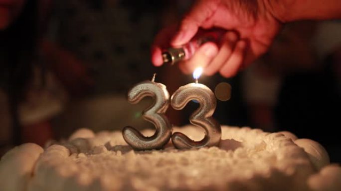 手持照明生日蛋糕蜡烛特写镜头，打火机庆祝33岁