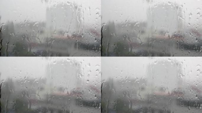 强烈的雨水冲向窗户玻璃并向下流动，关闭。雨季玻璃背景上的雨滴。4k