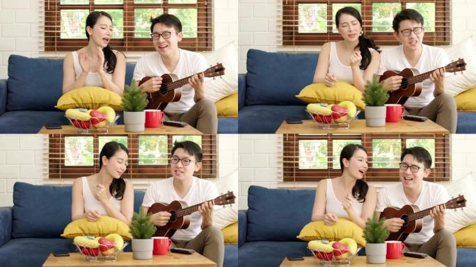 年轻的亚洲人嫁给快乐的夫妇在客厅里演奏四弦琴和唱歌，幸福的夫妇在家里一起放松周末