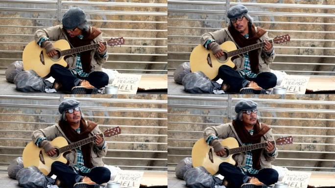 肮脏的无家可归的人坐着弹吉他