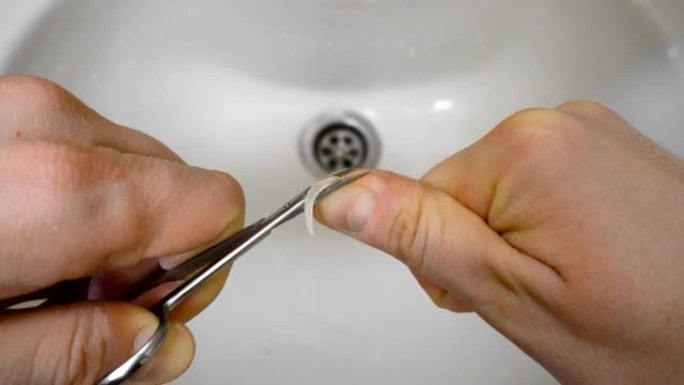 男性早上用剪刀在洗手盆或洗手盆上剪指甲